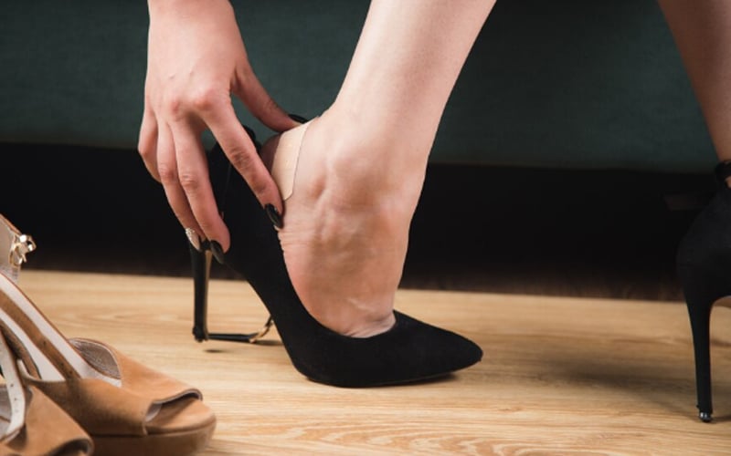 woman in high heels glues a plaster