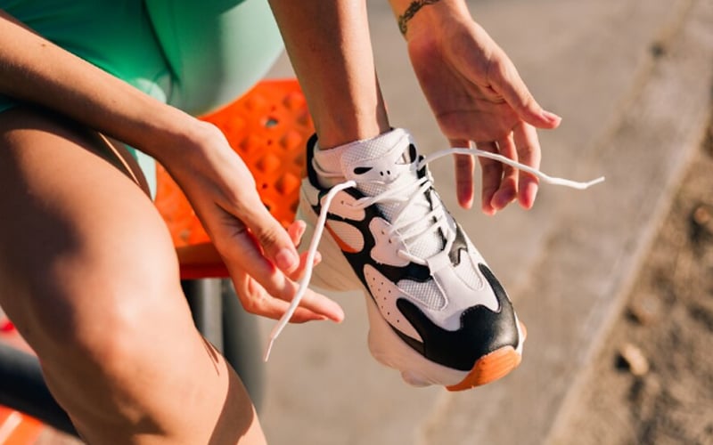 a woman tying the shoelaces of the sneakers